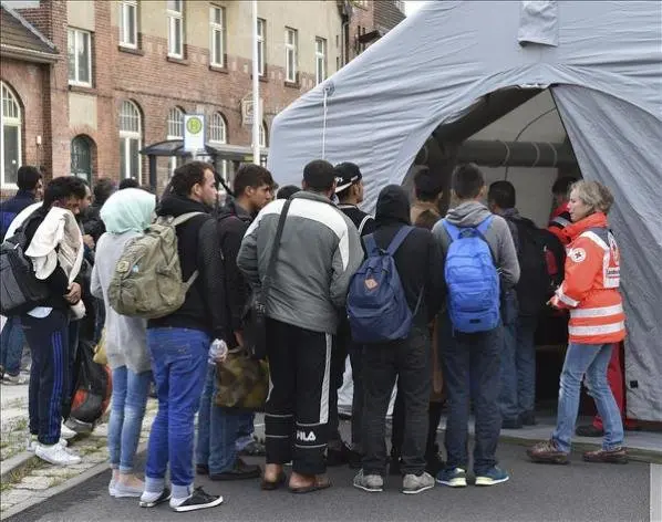 Refugiados sirios hacen cola hoy en una tienda de campaña de la Cruz Roja para un registro médico tras llegar a Eisenhuettenstadt (Alemania). EFE