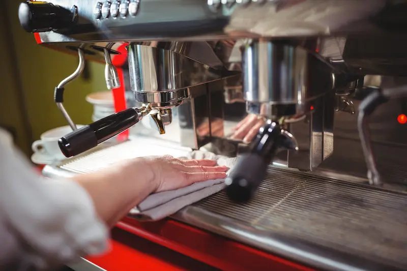 Camarera limpiando máquina de café