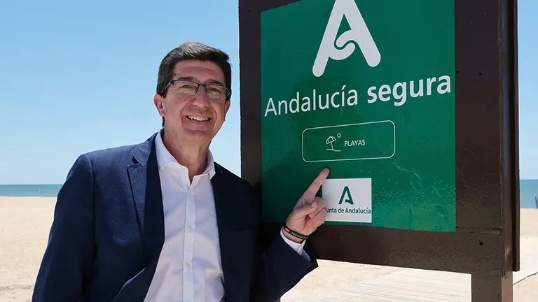 El vicepresidente Juan Mar&iacute;n junto al distintivo 'Andaluc&iacute;a Segura' en una playa.