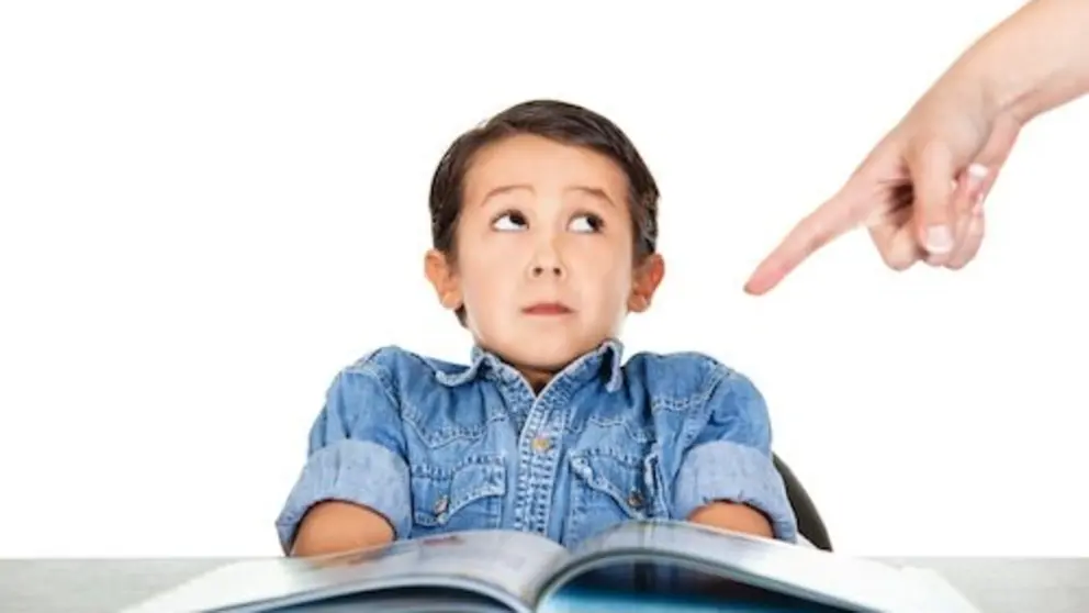 Finger pointing at the school book. Little boy looking frightened.